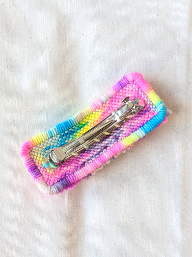 This is an image of a medium sized punch needle hair barrettes made with a rainbow yarn. Dancing arms punch needle hair accessories.