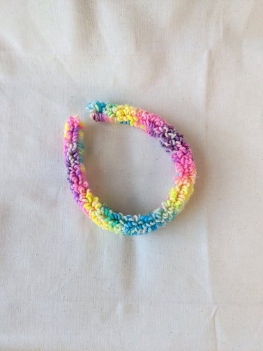 This is a detail image of a rainbow looped punch needle headband. The colors ranges from bright yellow to teal to pink to purple. Holo Rainbow Headband 01 | dancing arms | Punch Needle Headband