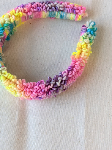 This is a detail image of a rainbow looped punch needle headband. The colors ranges from bright yellow to teal to pink to purple. Holo Rainbow Headband 01 | dancing arms | Punch Needle Hair Accessories