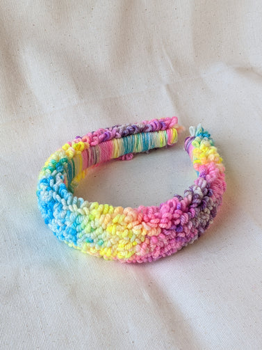 This is a detail image of a rainbow looped punch needle headband. The colors ranges from bright yellow to teal to pink to purple. Holo Rainbow Headband 01 | dancing arms | Punch Needle Headband