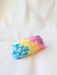 This is an image of a small sized punch needle hair barrettes made with a rainbow yarn. Dancing arms punch needle hair accessories.