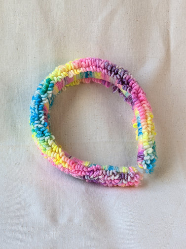 This is a detail image of a rainbow looped punch needle headband. The colors ranges from bright yellow to teal to pink to purple. Holo Rainbow Headband 01 | dancing arms | Punch Needle Headband